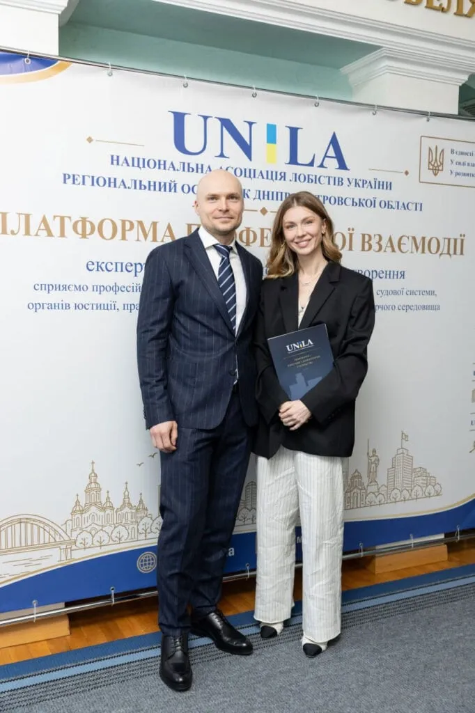 Павло Гезь та учасниця заходу біля банера UNILA